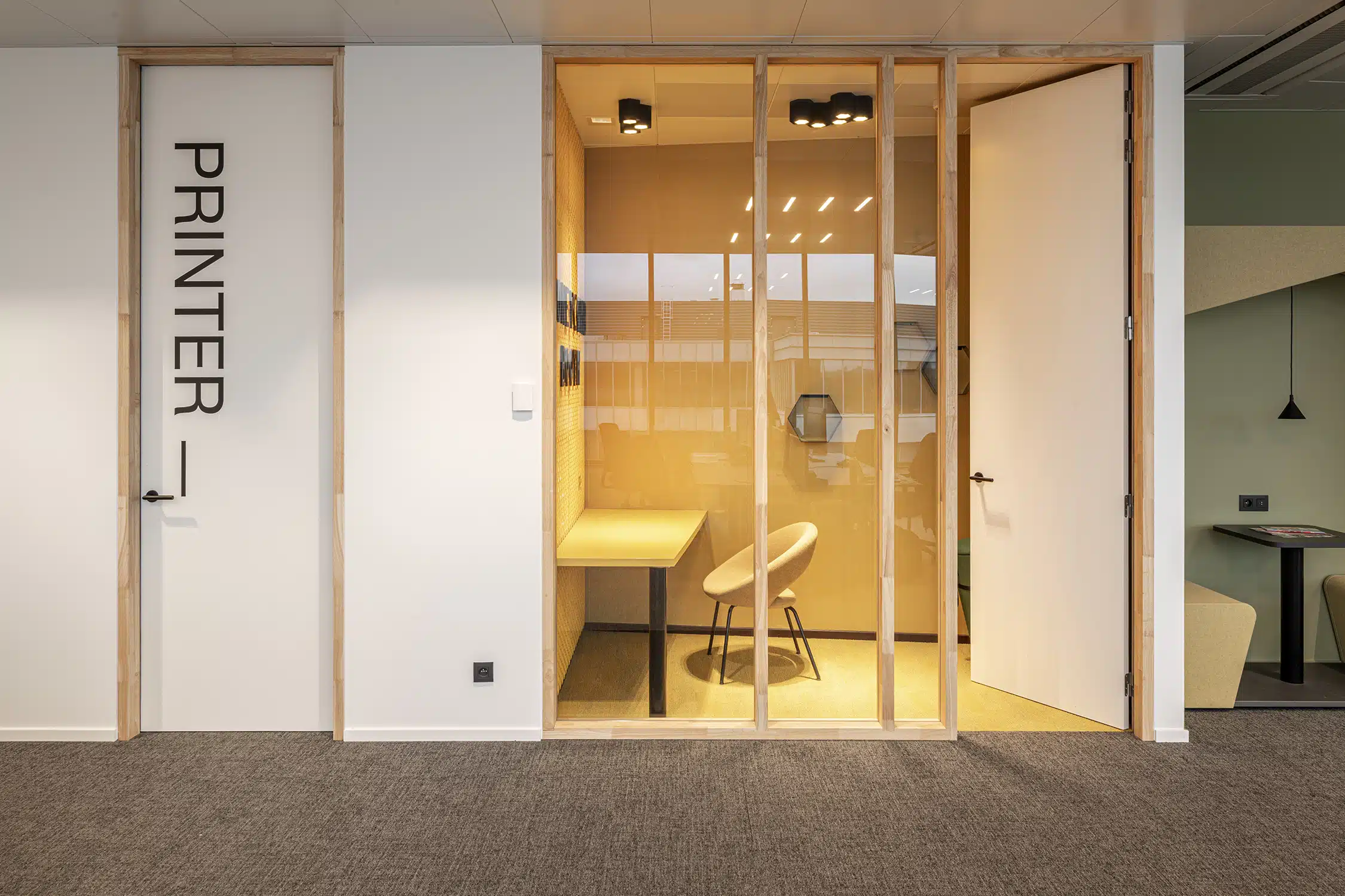 Geluidsisoleerde phone booth met glazen wanden en houten frame in het kantoor van Compass Group Belgium HQ, Brussel – interie